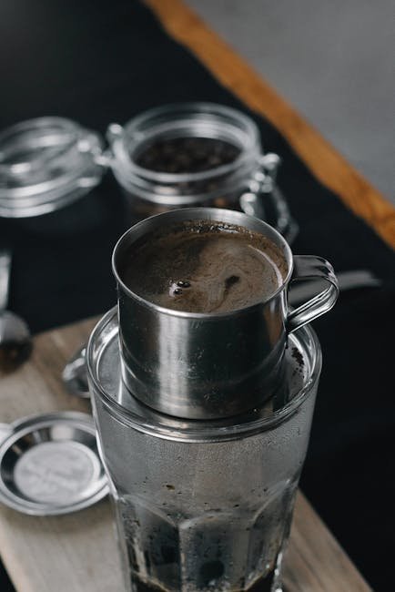 A close-up of Vietnamese coffee brewed with a phin filter over a glass. Rich, aromatic coffee experience.